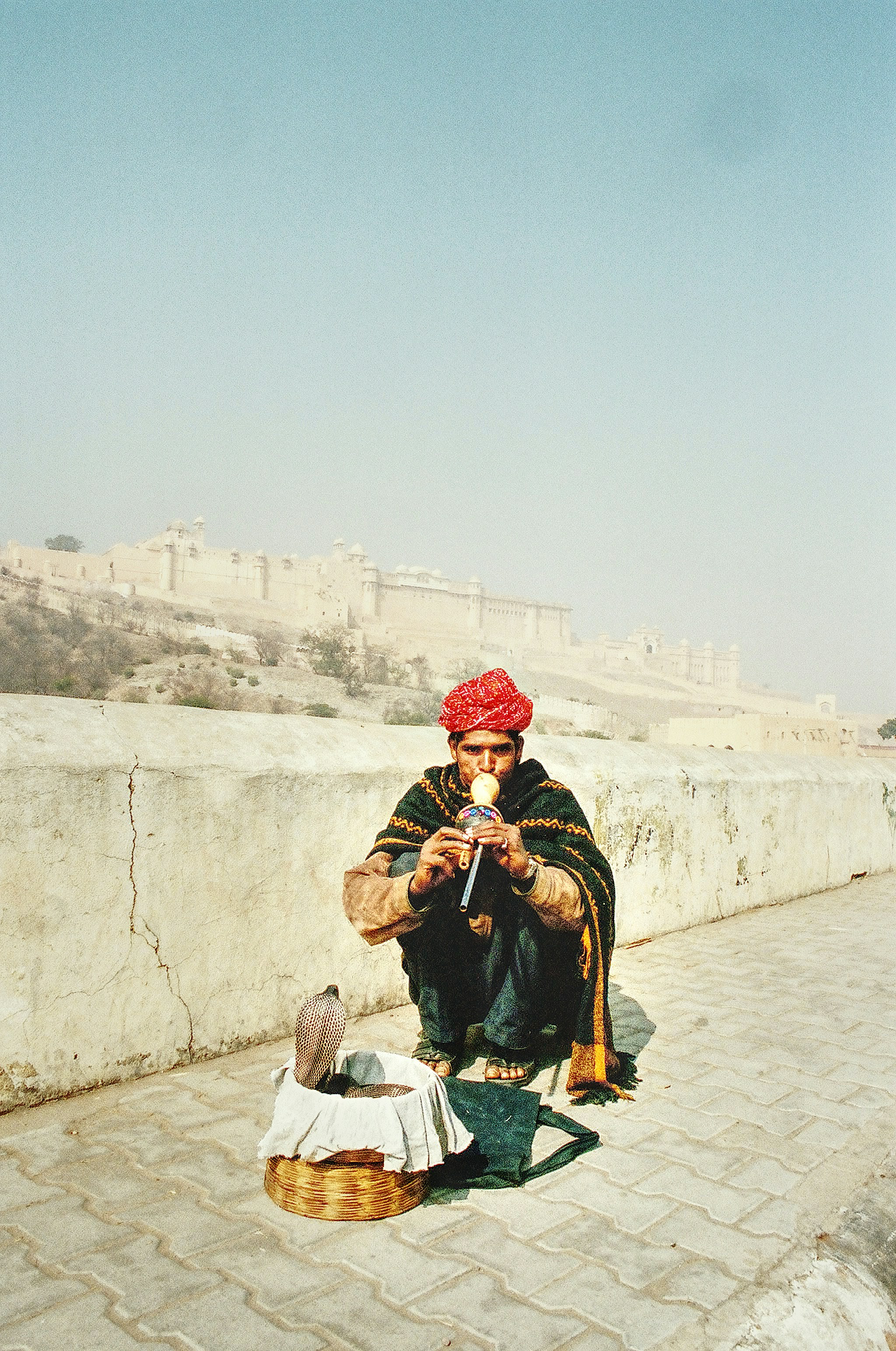 man in red and white plaid scarf sitting on gray concrete bench during daytime