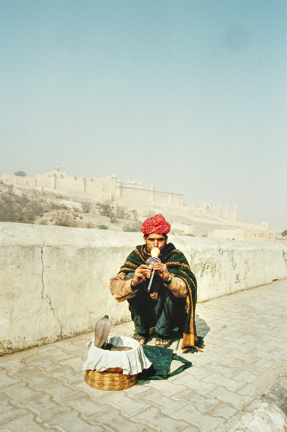 man in red and white plaid scarf sitting on gray concrete bench during daytime