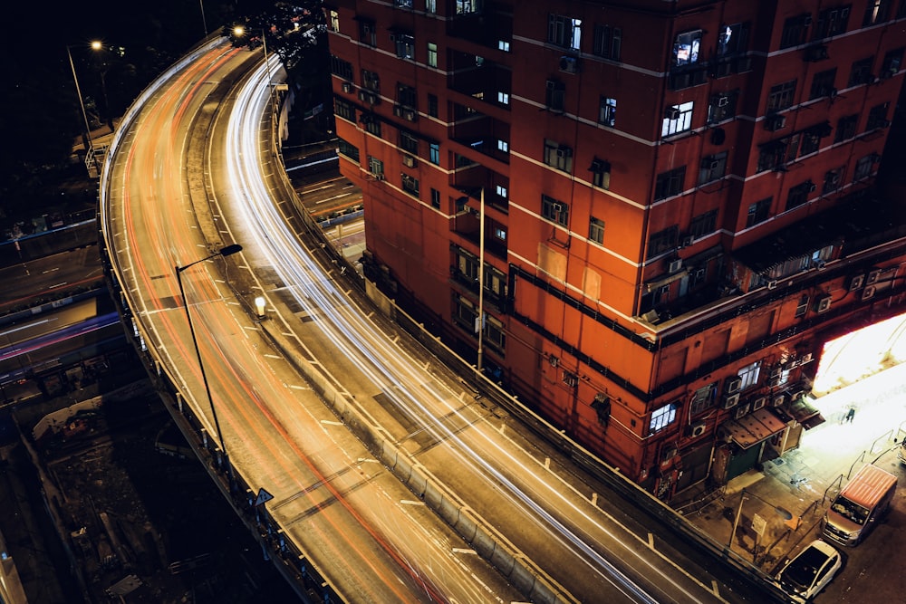 time lapse photography of cars on road near brown building during night time