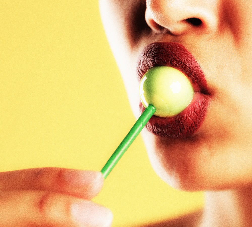 woman holding green lollipop with yellow background