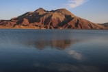 A serene mountain lake reflecting the clear blue sky at sunrise