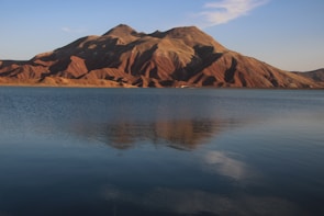 A serene mountain lake reflecting the clear blue sky at sunrise