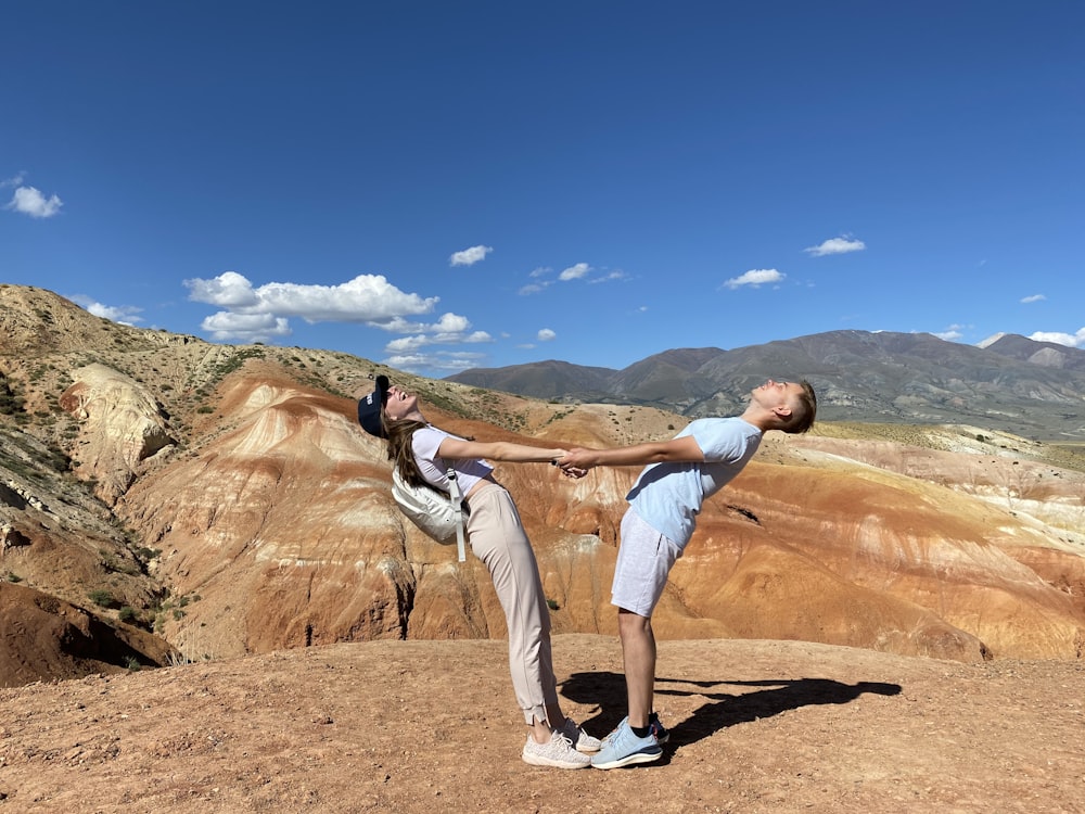 man in white t-shirt and white shorts standing on brown rock formation during daytime