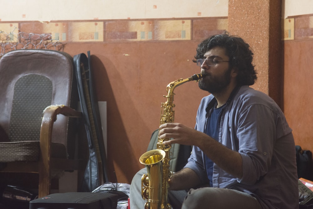 man in blue and white plaid button up shirt playing saxophone