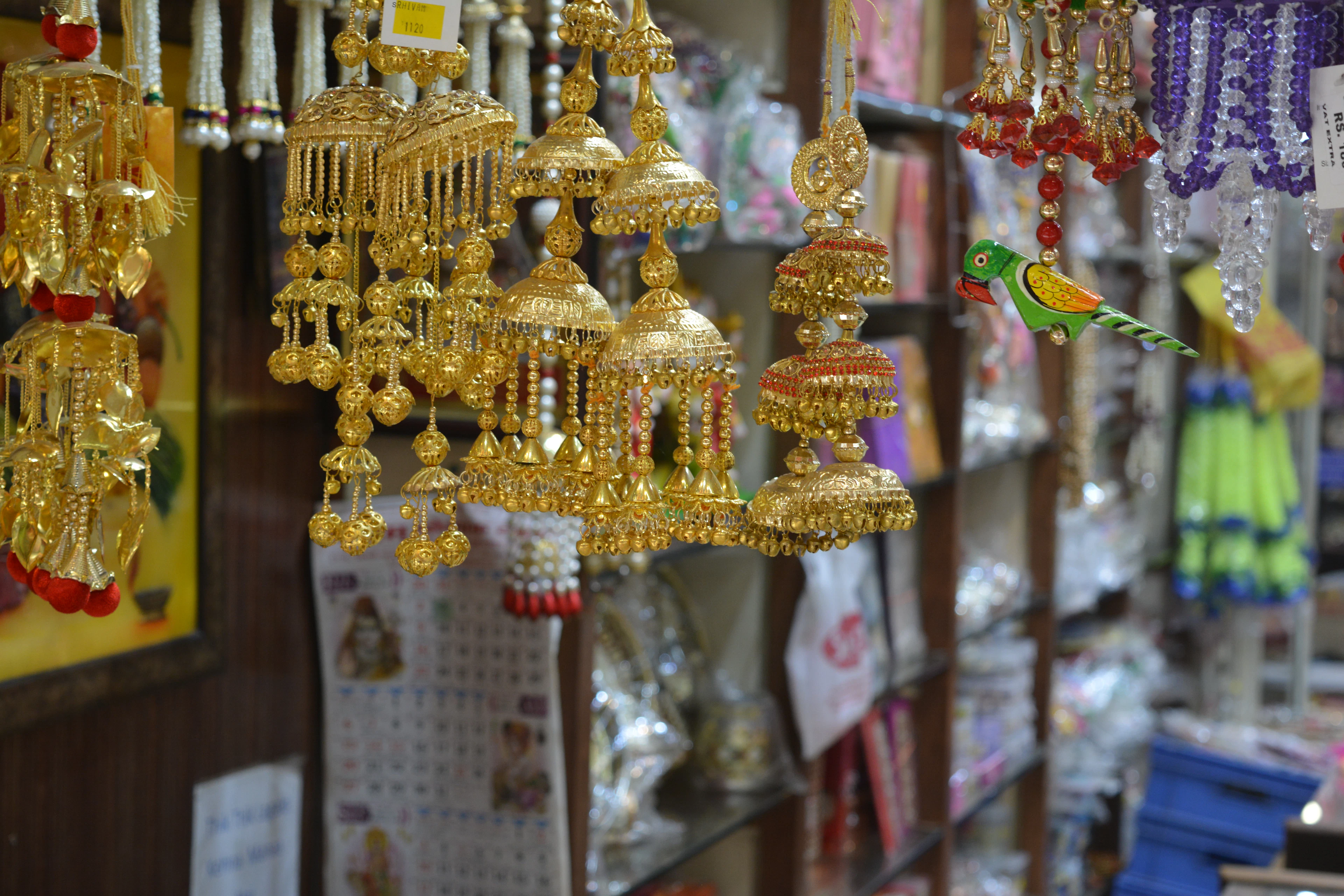 A market stall hung with gold jhumka earrings, bangles and beaded wedding decorations.