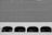 A building facade featuring a grid of small squares above a row of white arched windows. Each window opening reveals a dark interior, with the white grid structure dominating the upper part of the image. The entire scene is rendered in black and white.