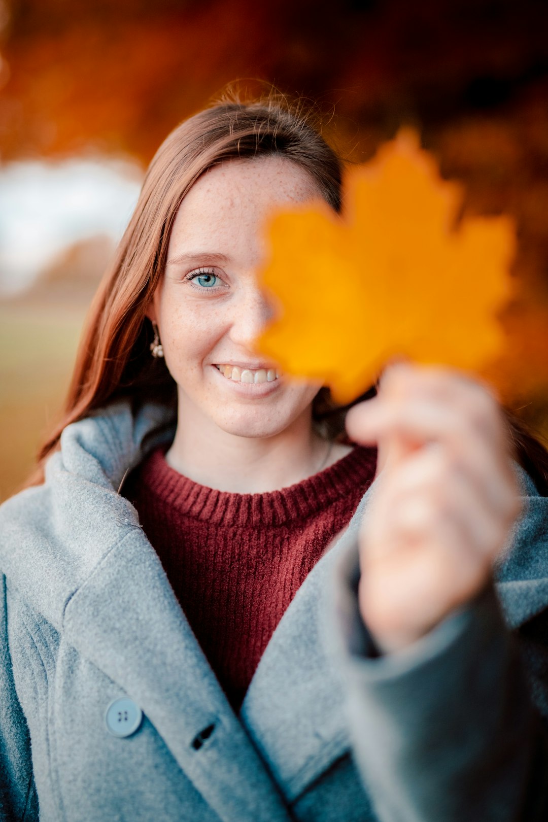 woman in red turtleneck sweater holding yellow maple leaf