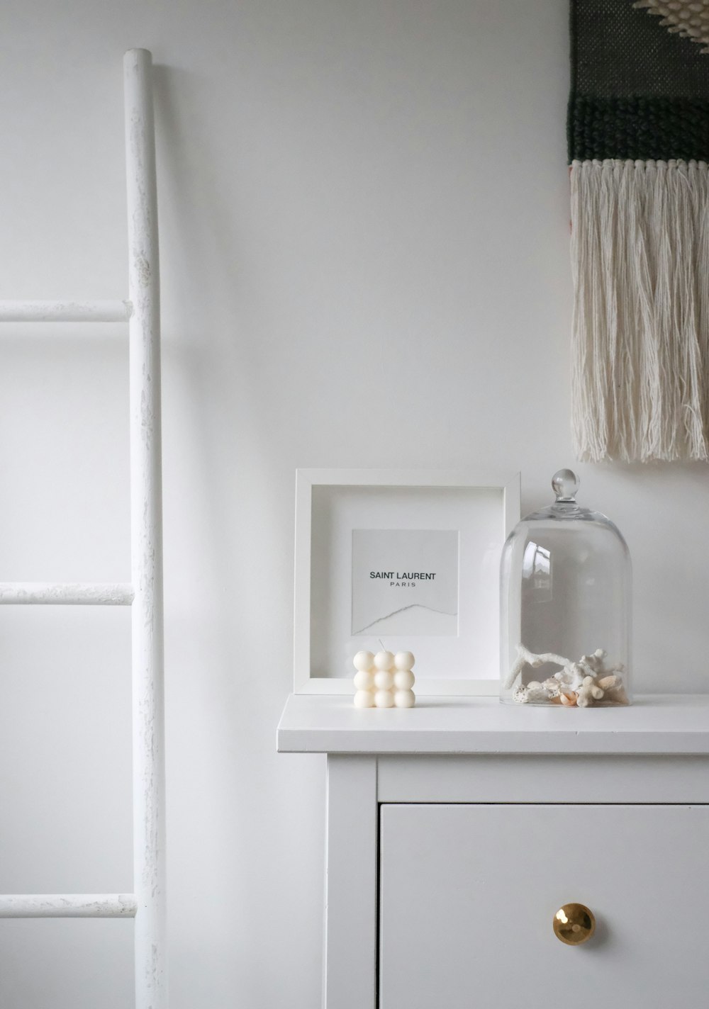 a white dresser with a white shelf and a white ladder