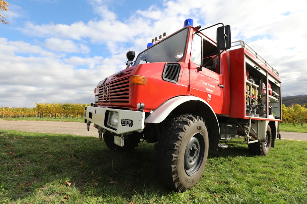 red and white truck on green grass field under blue sky during daytime