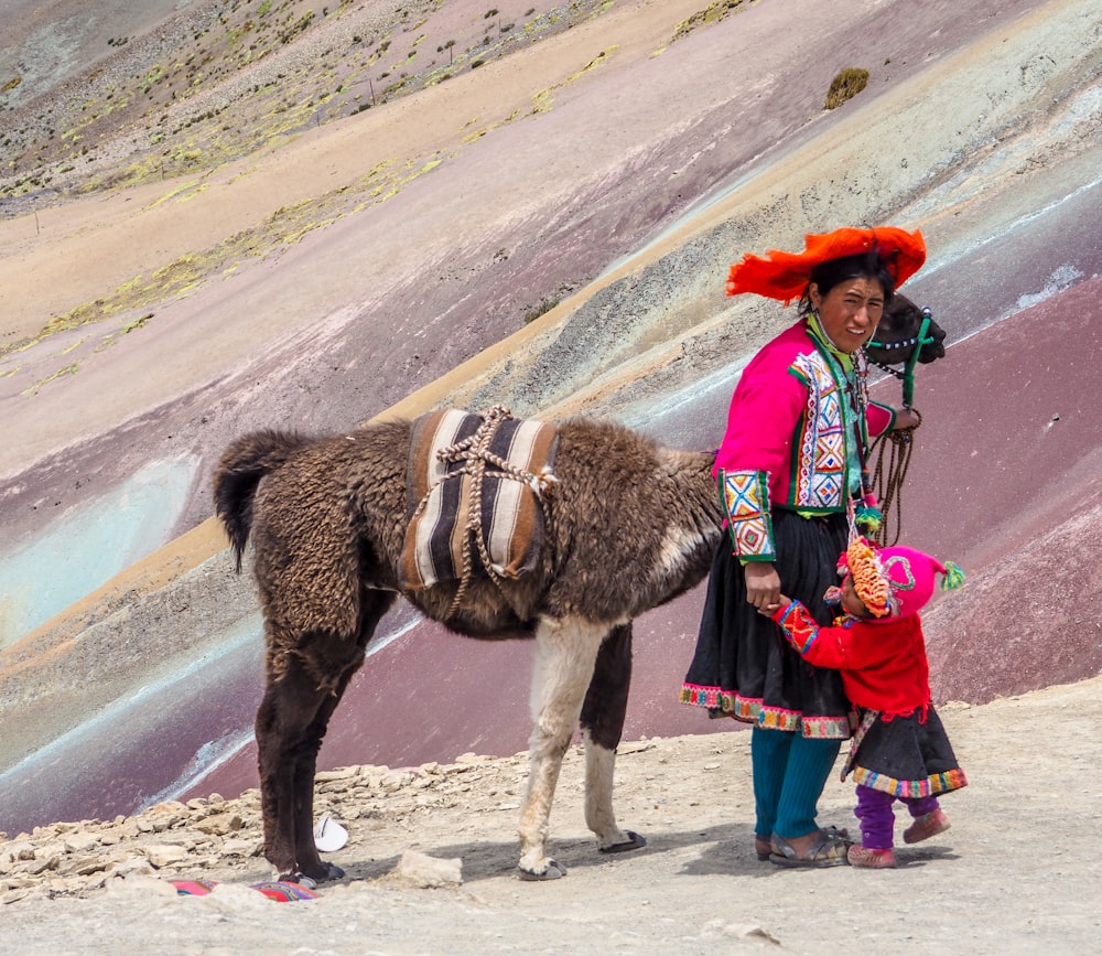 woman in red and blue dress riding brown horse during daytime