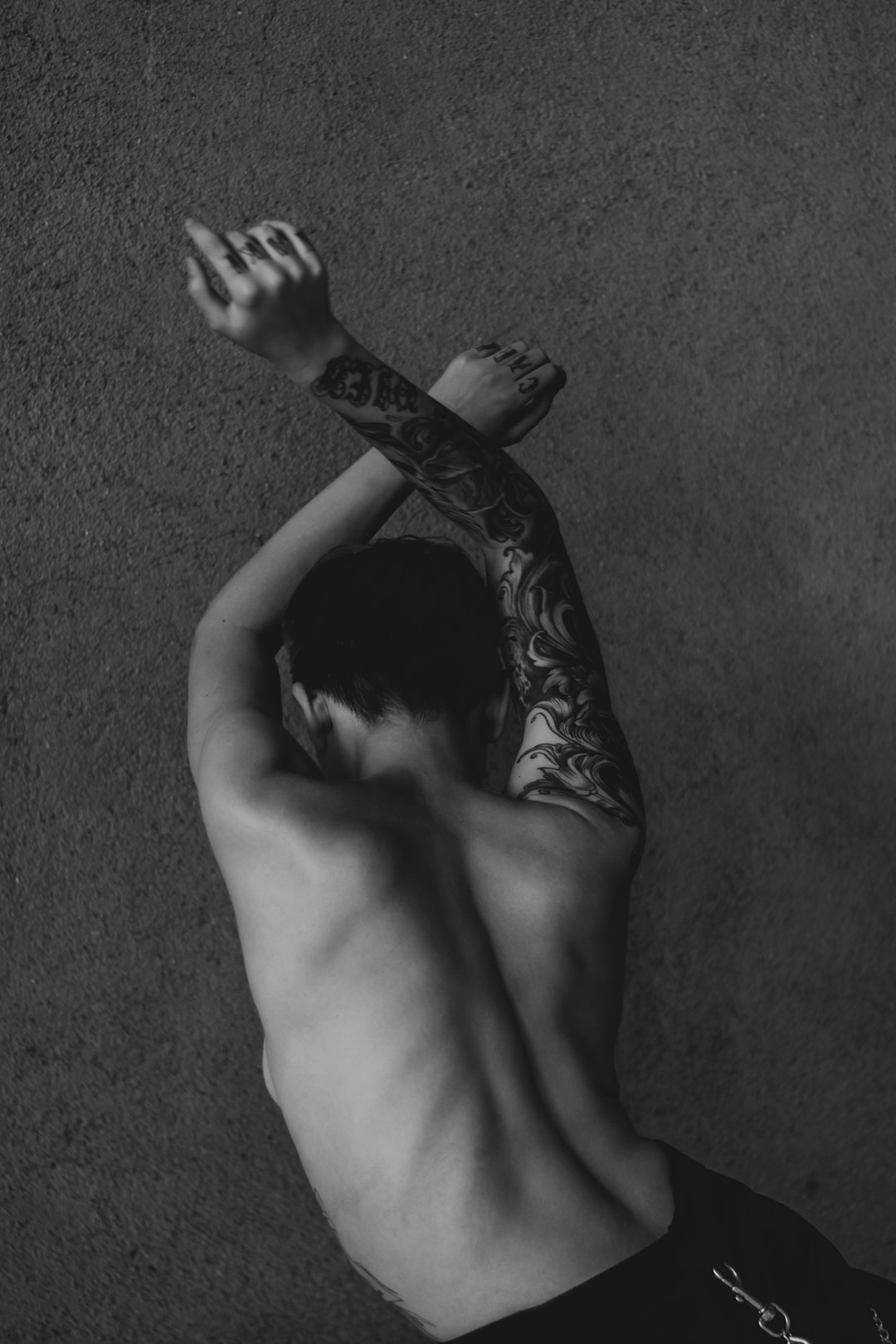 grayscale photo of topless man lying on floor