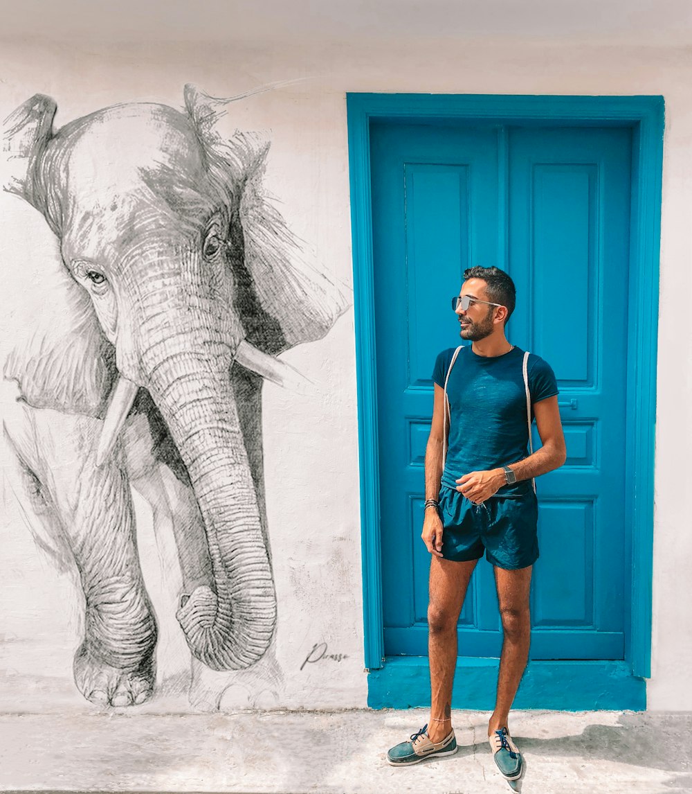 woman in blue tank top standing beside elephant