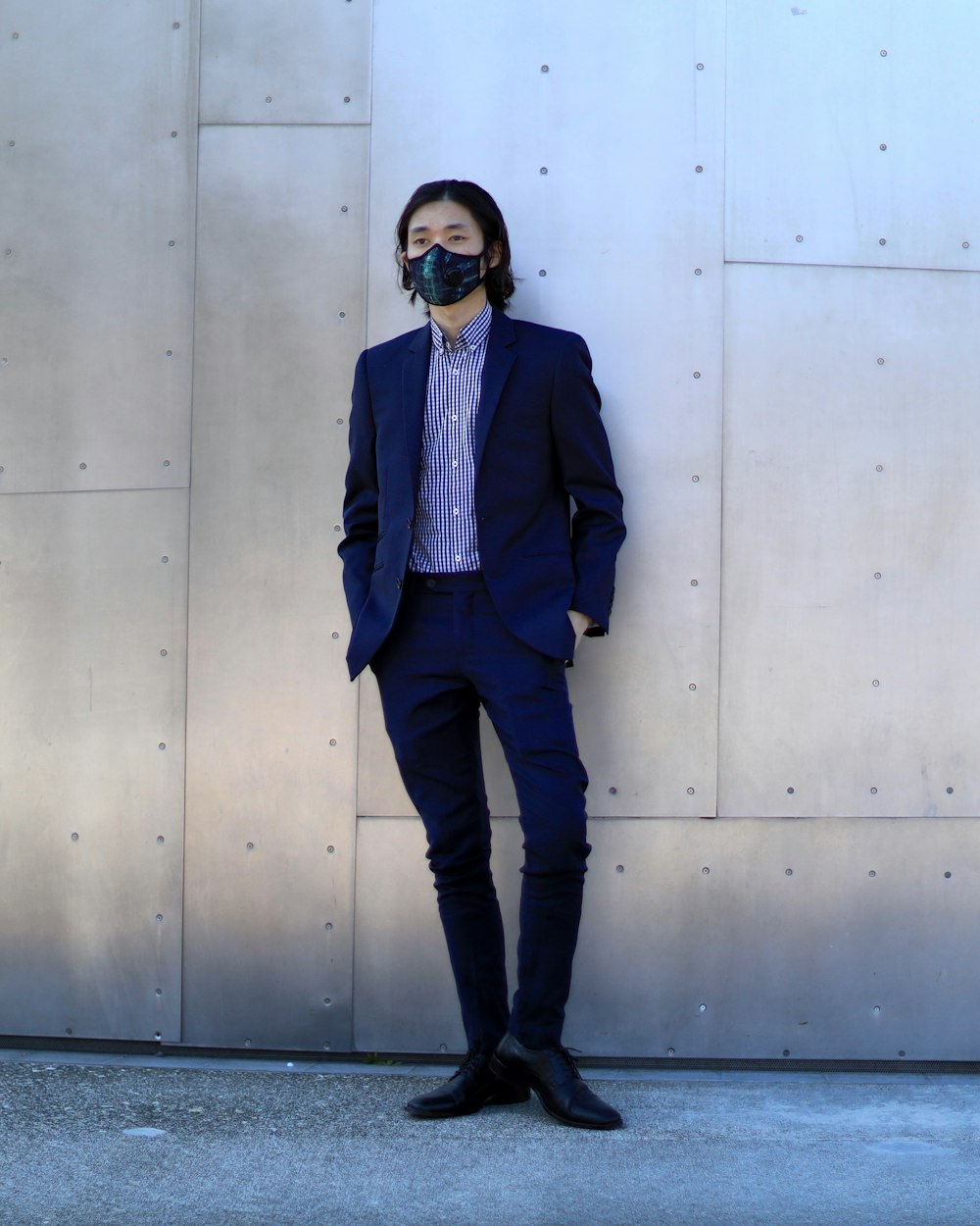 man in gray suit jacket standing beside gray wall