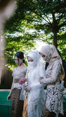 woman in white floral dress standing beside woman in brown hijab
