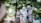 A bride dressed in white lace and holding a bouquet of flowers is accompanied by two women in traditional attire. They are walking outdoors surrounded by lush green trees, creating a serene and intimate atmosphere.