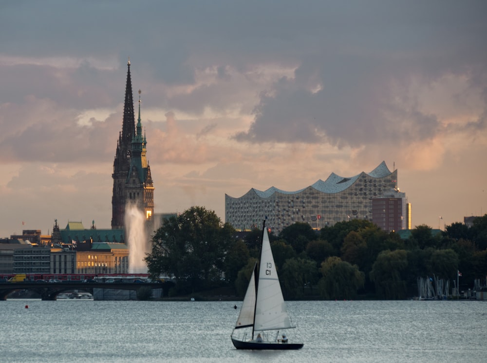 white sailboat on water near city buildings during daytime