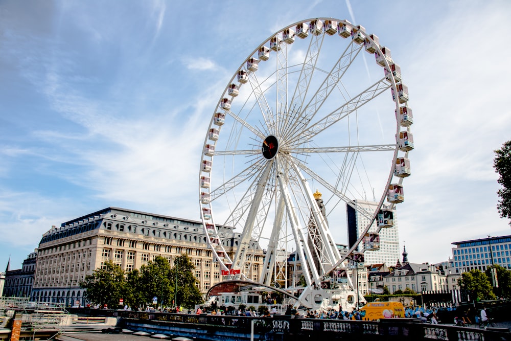 Grande roue blanche près d’un bâtiment brun pendant la journée