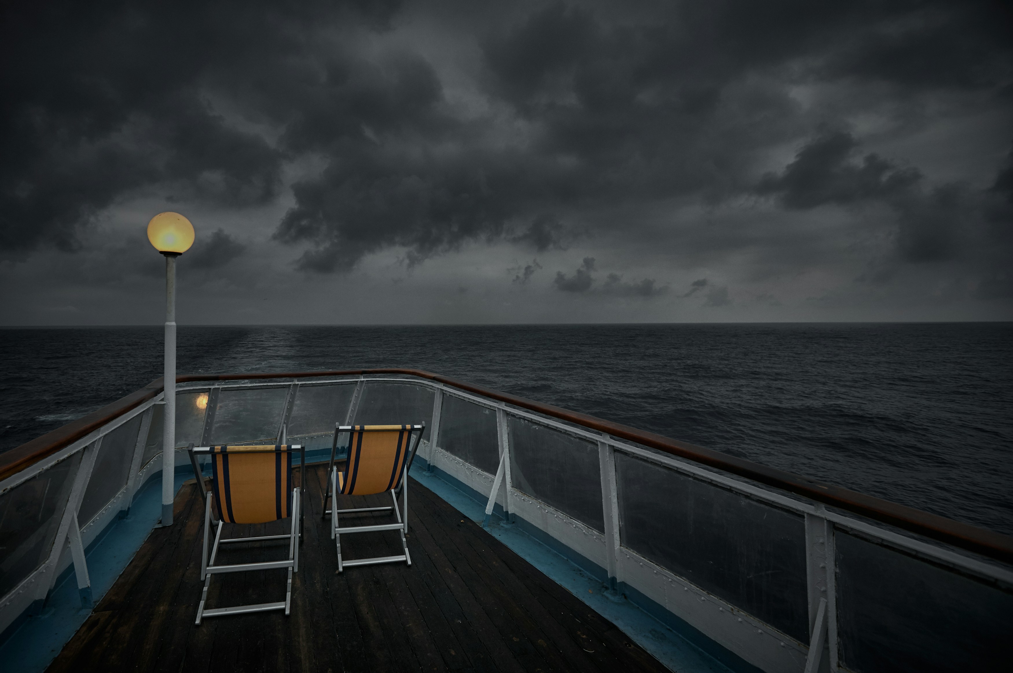 white and yellow boat on sea under gray clouds, Sailing at Night.