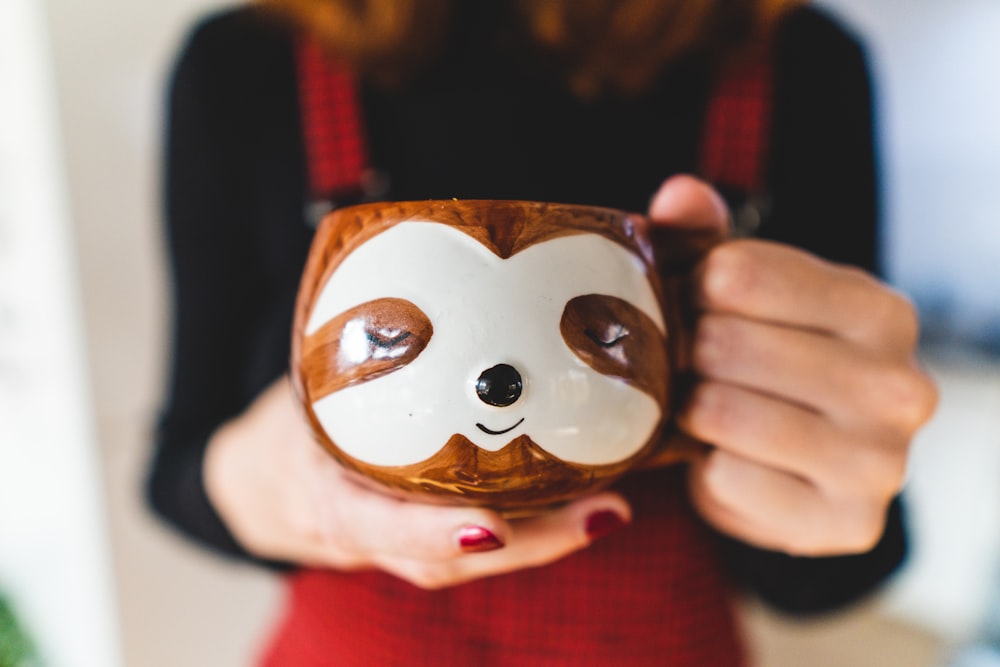 person holding brown and white ceramic owl figurine