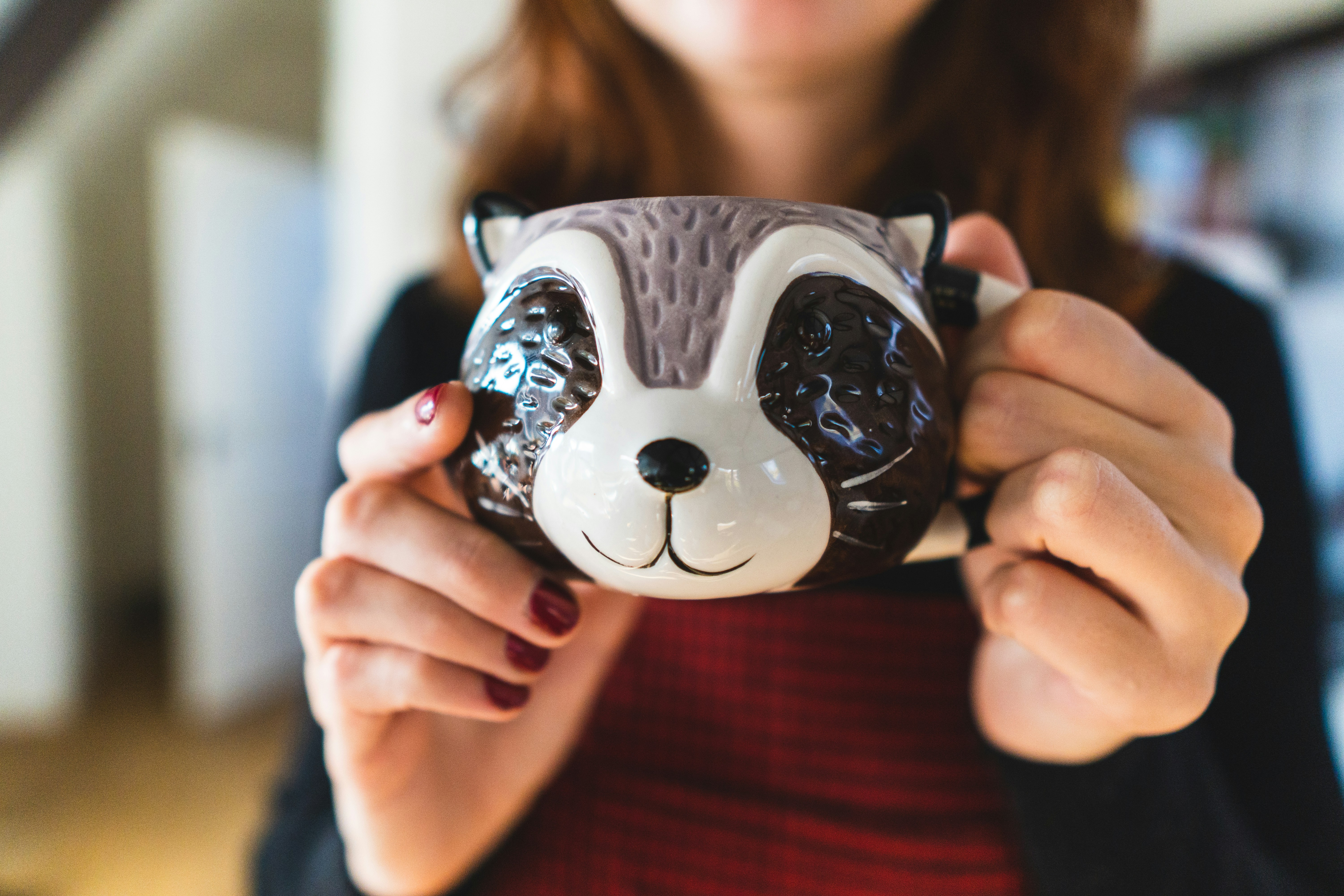 woman in red shirt holding white and blue ceramic skull figurine
