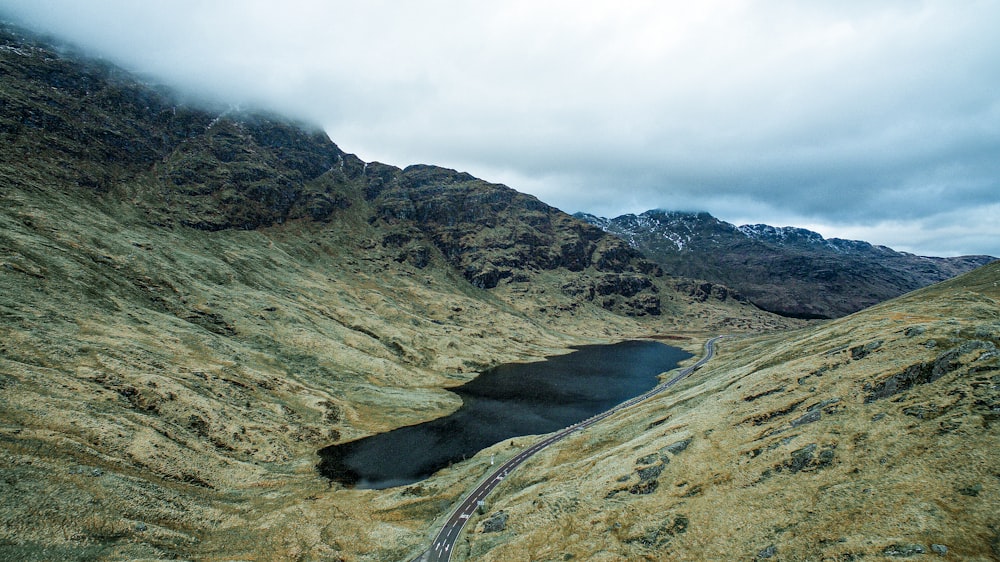 Carretera de asfalto gris entre montañas marrones bajo cielo nublado blanco durante el día