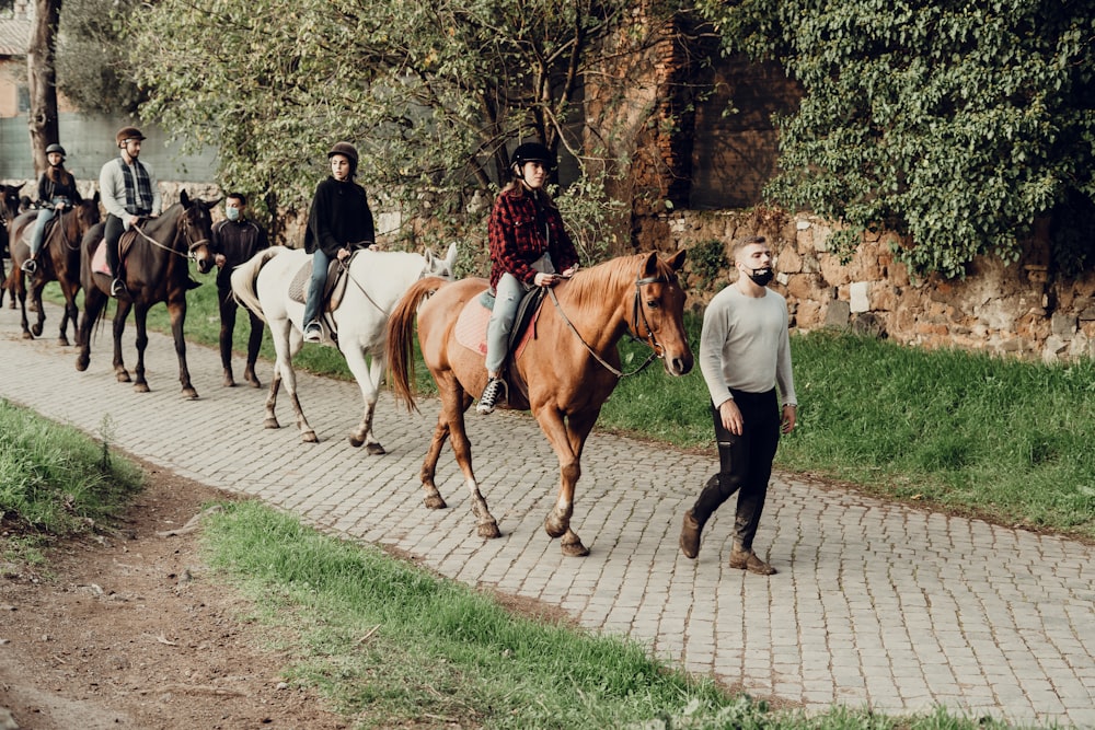 man in white long sleeve shirt and black pants walking beside brown horse during daytime