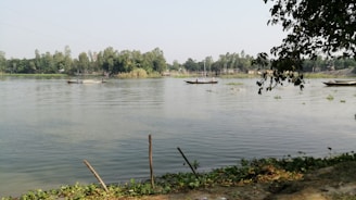 A small boat and inflatable tubes floating on the calm river under clear skies.