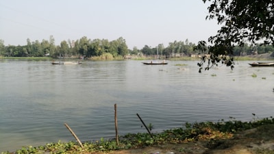 A small boat and inflatable tubes floating on the calm river under clear skies.
