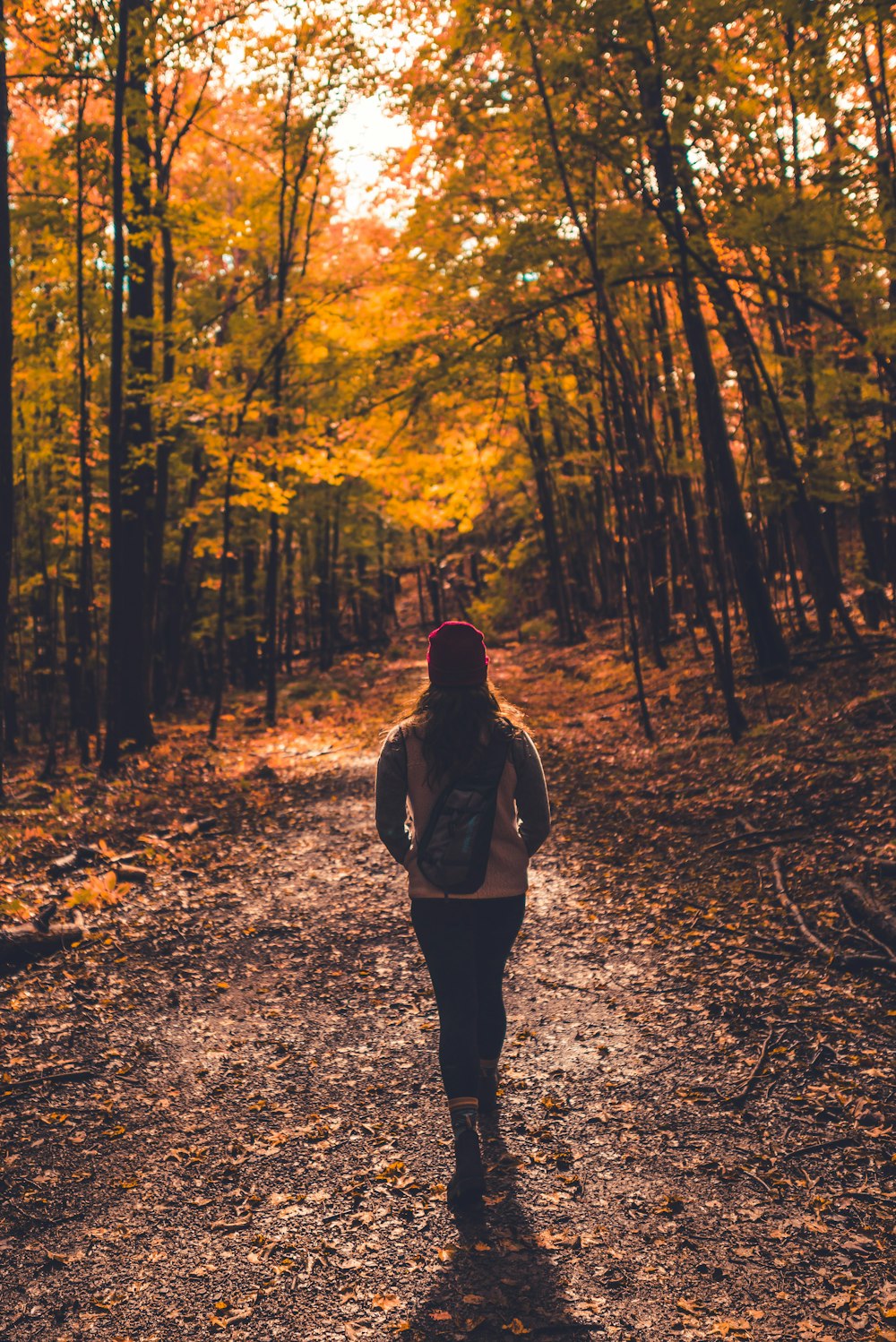 a woman is walking down a path in the woods