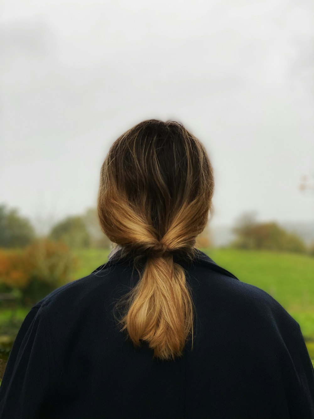 woman in black hoodie standing on green grass field during daytime