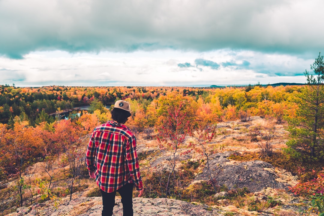 man in red and black plaid dress shirt standing on brown field during daytime