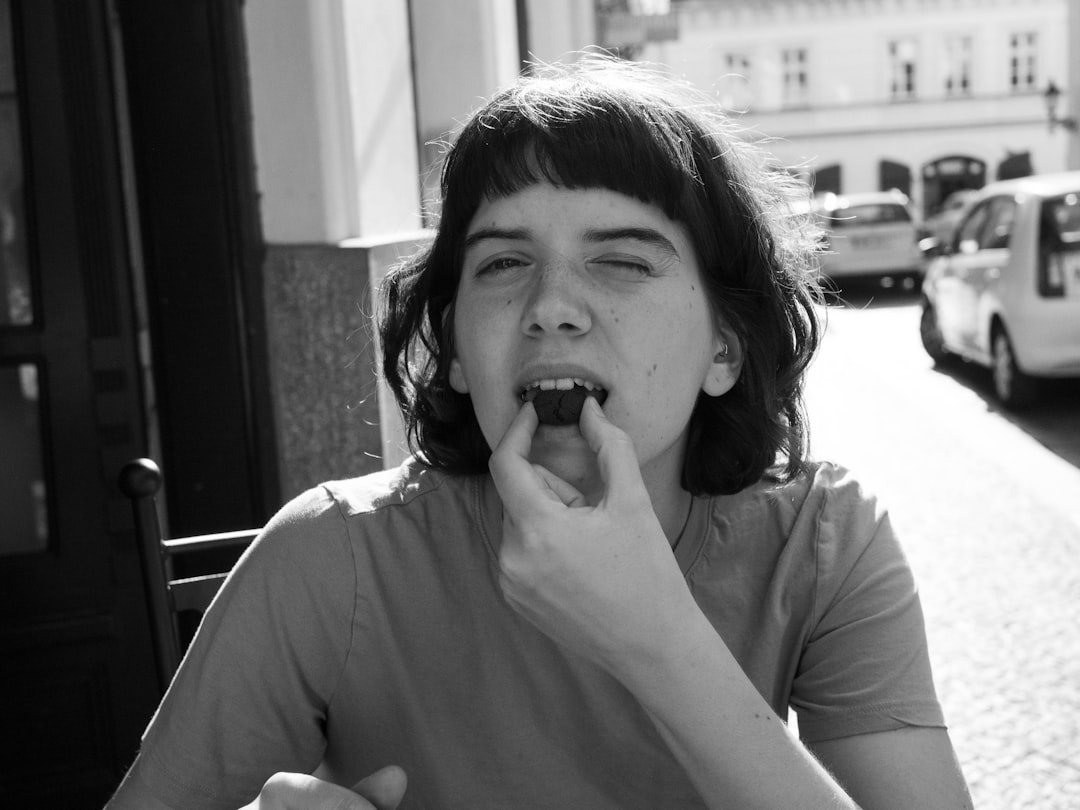 black and white photo of young woman about to put her fingers in her mouth and blow. 