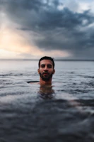 man in water under cloudy sky during daytime