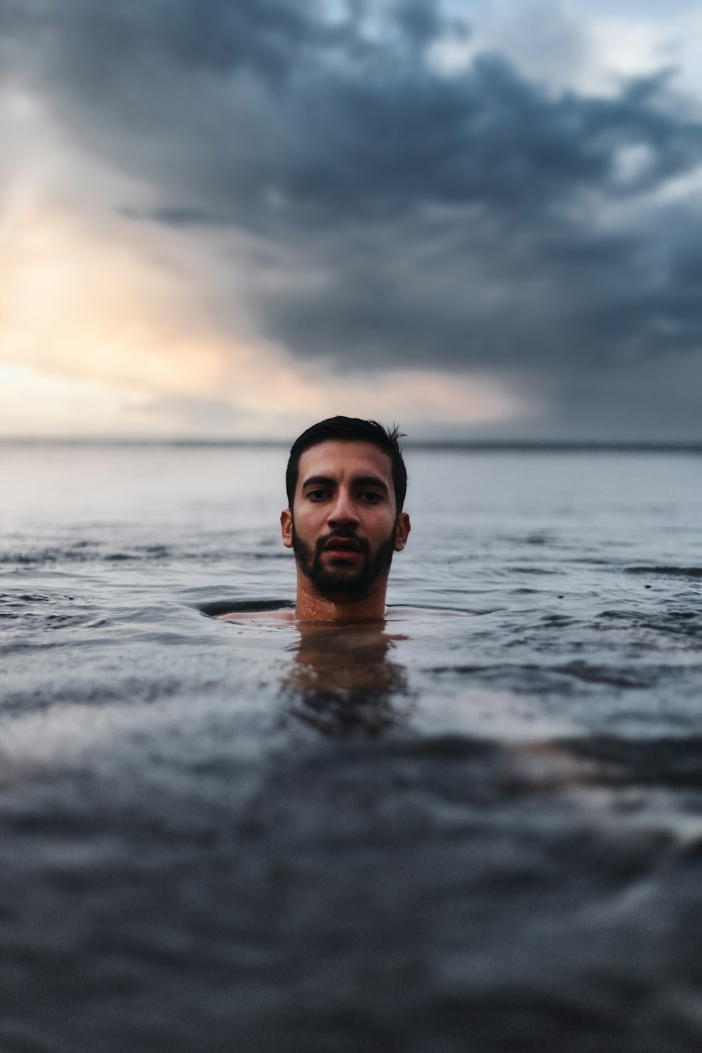 man in water under cloudy sky during daytime