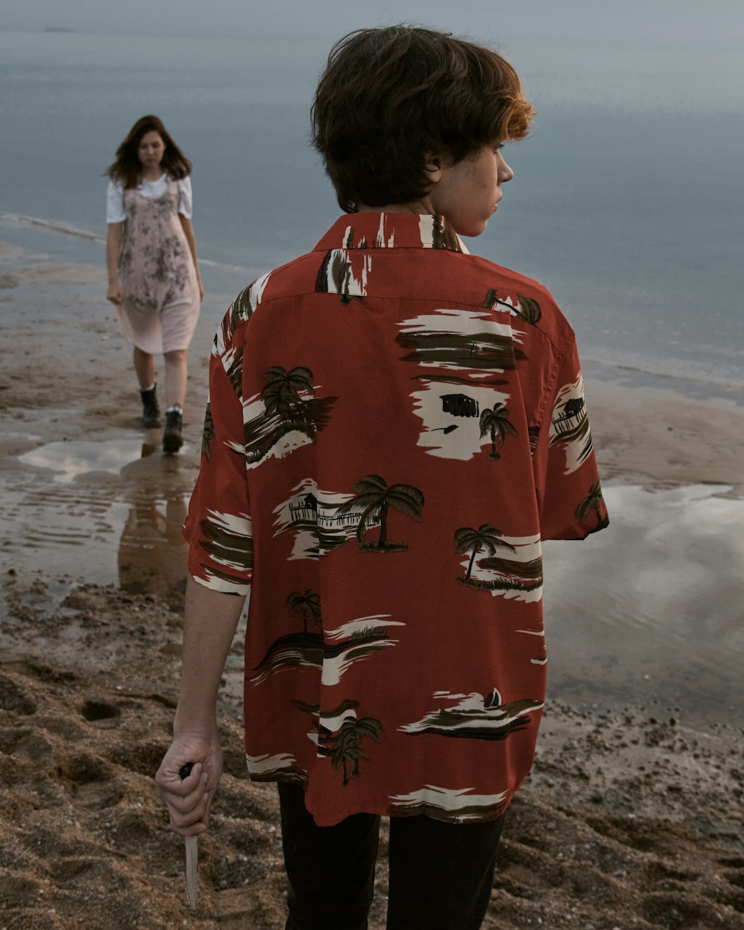 man in red and white floral long sleeve shirt standing on beach during daytime