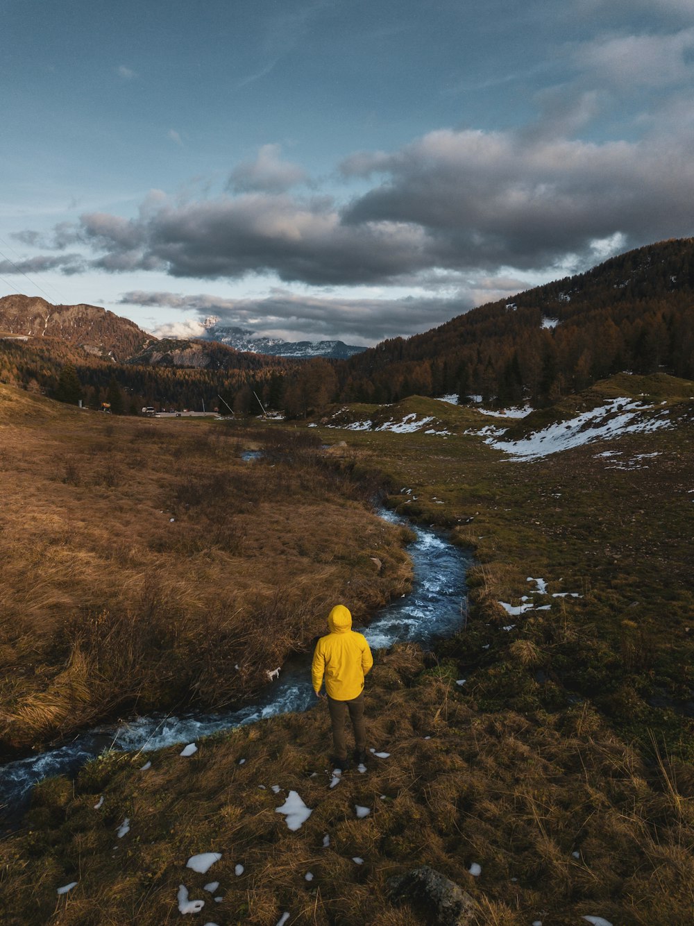 person in yellow hoodie standing on brown field during daytime