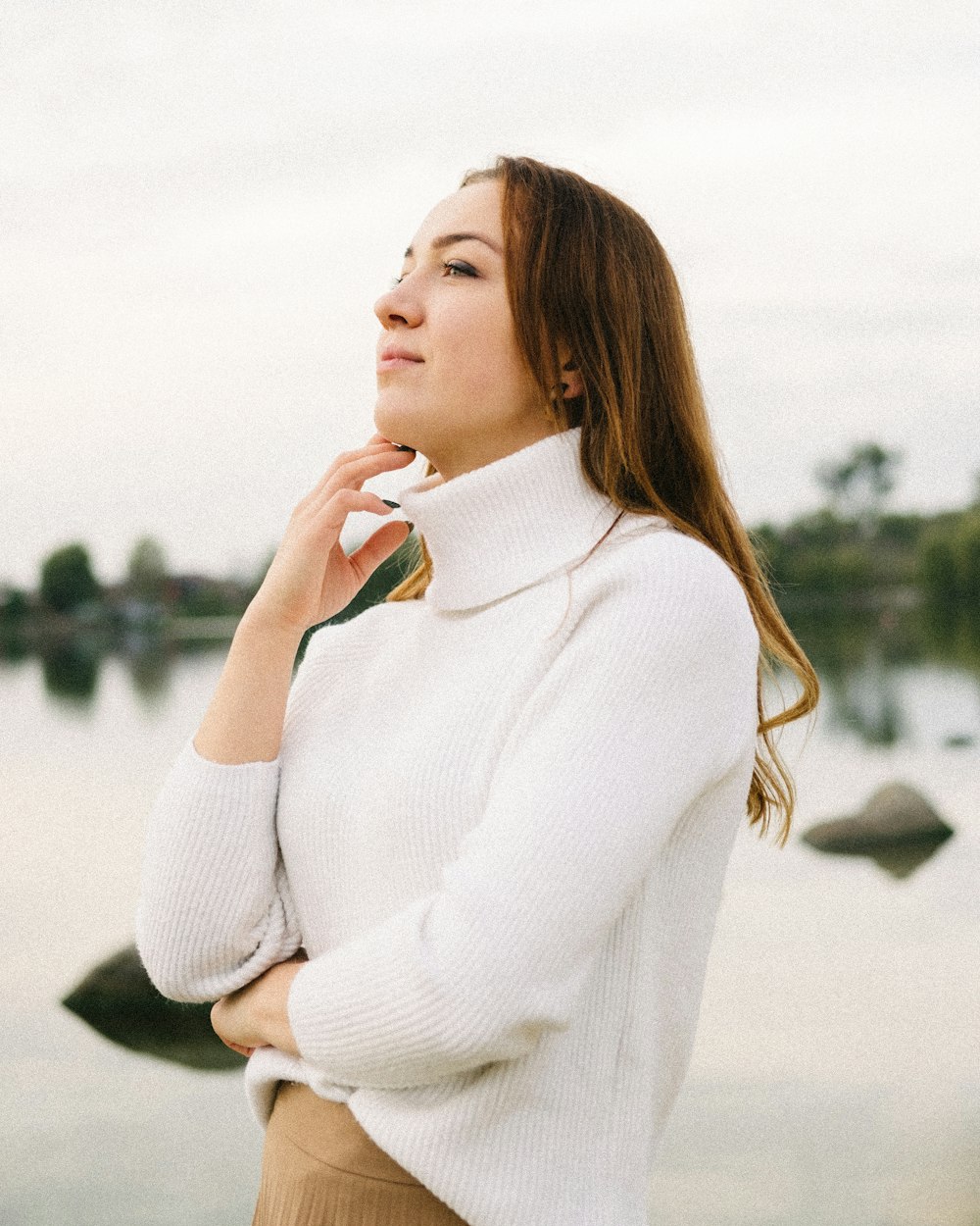 woman in white turtleneck sweater standing on gray concrete floor during daytime