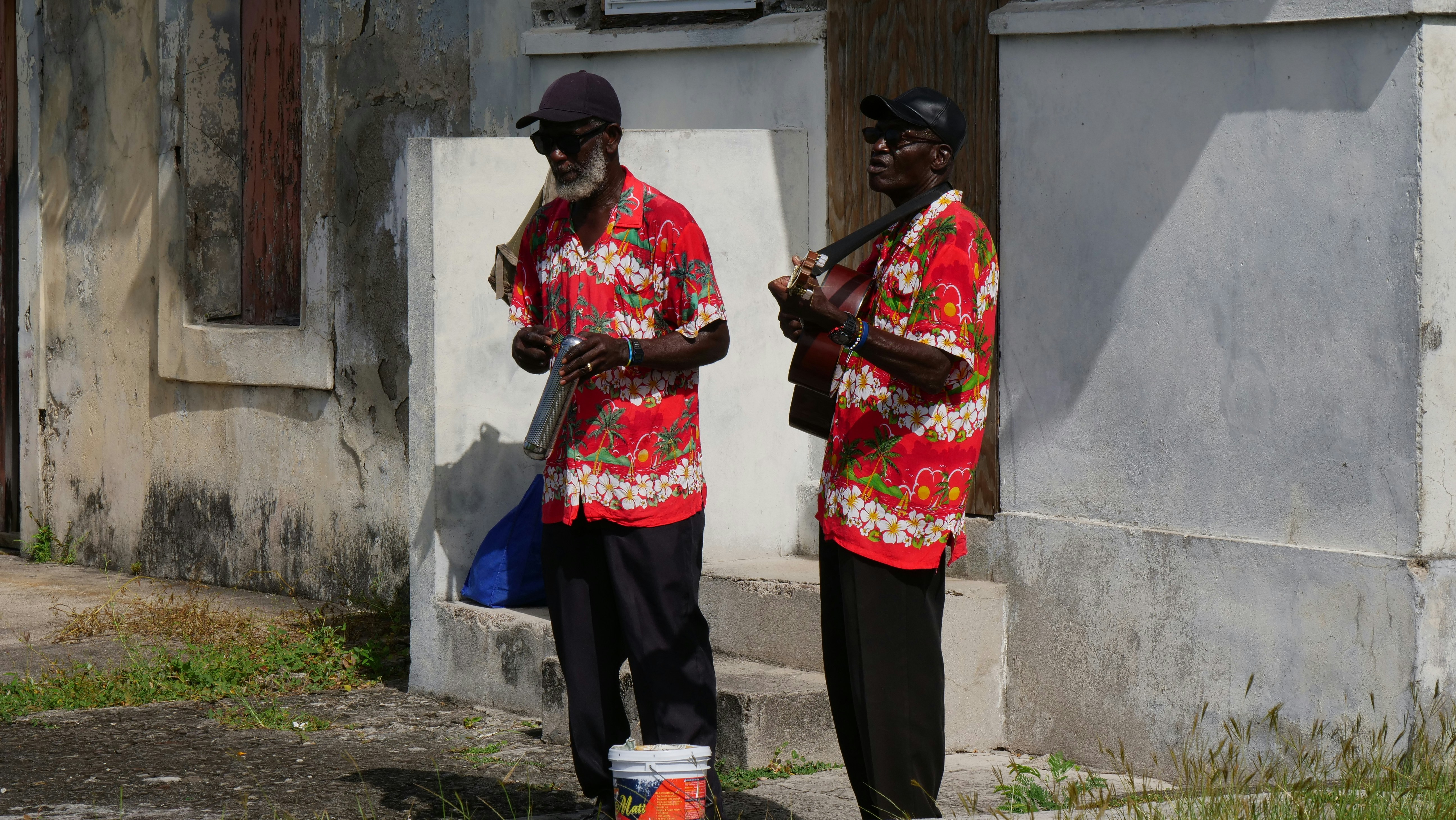 man in red and white floral button up shirt and black pants standing beside woman in during