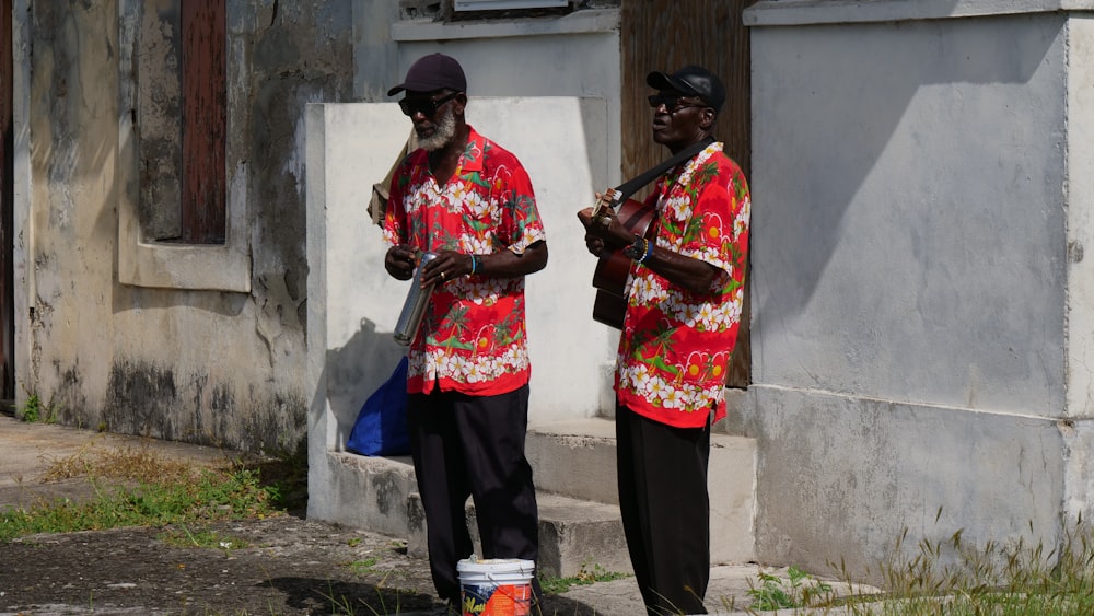 man in red and white floral button up shirt and black pants standing beside woman in during