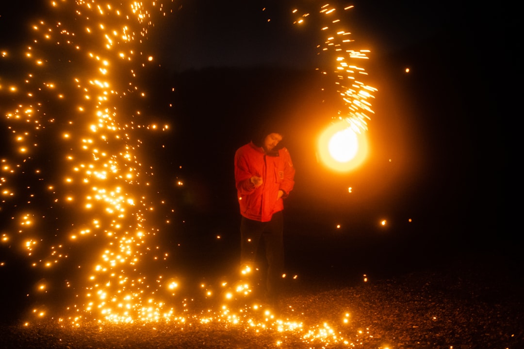 man in red hoodie standing on snow covered ground during night time