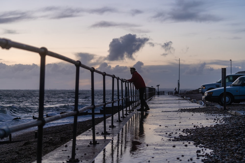 homme en chemise rouge debout sur la plage pendant la journée