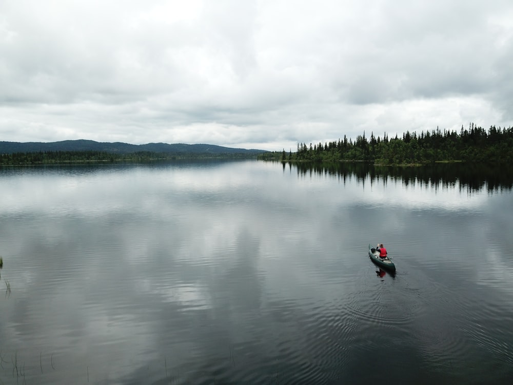 personne en veste rouge montant sur le kayak rouge sur le lac pendant la journée