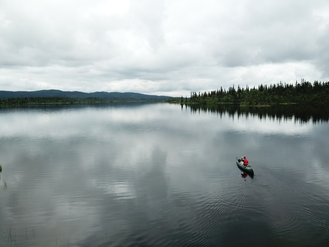 person in red jacket riding on red kayak on lake during daytime