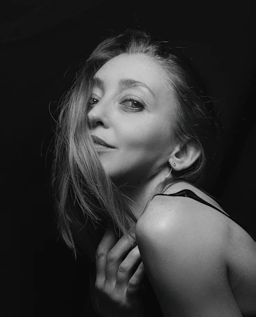 A striking black and white portrait of a woman bathed in soft natural light, showcasing intimate emotion.