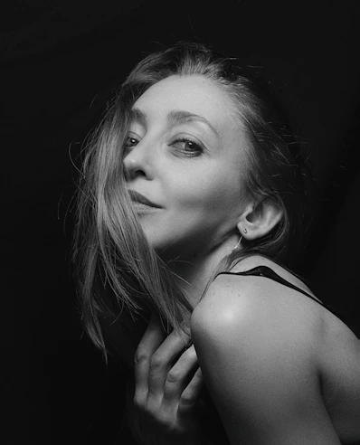 A striking black and white portrait of a woman with soft natural light highlighting her features.