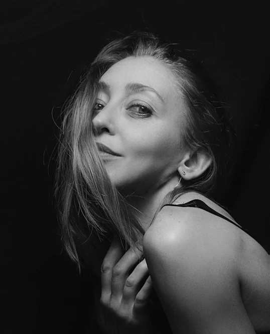 Black and white portrait of a woman softly lit, evoking deep emotion.
