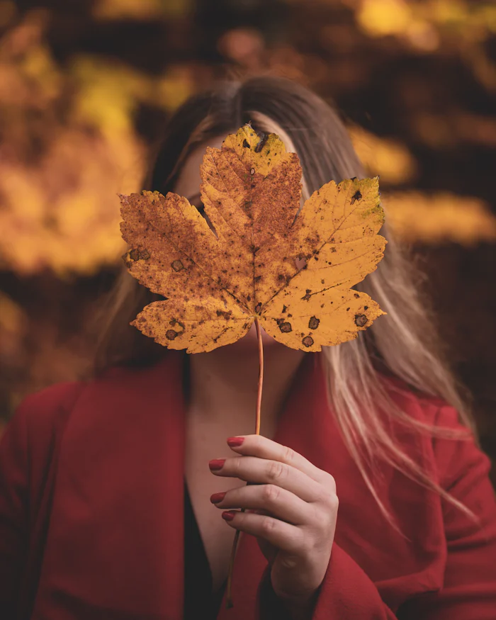 Woman in a red long sleeve top holding a maple leaf
