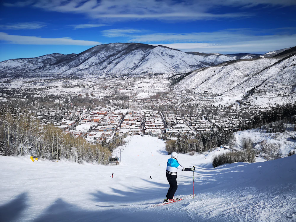 A skier looking down over a mountain town at the end of the day