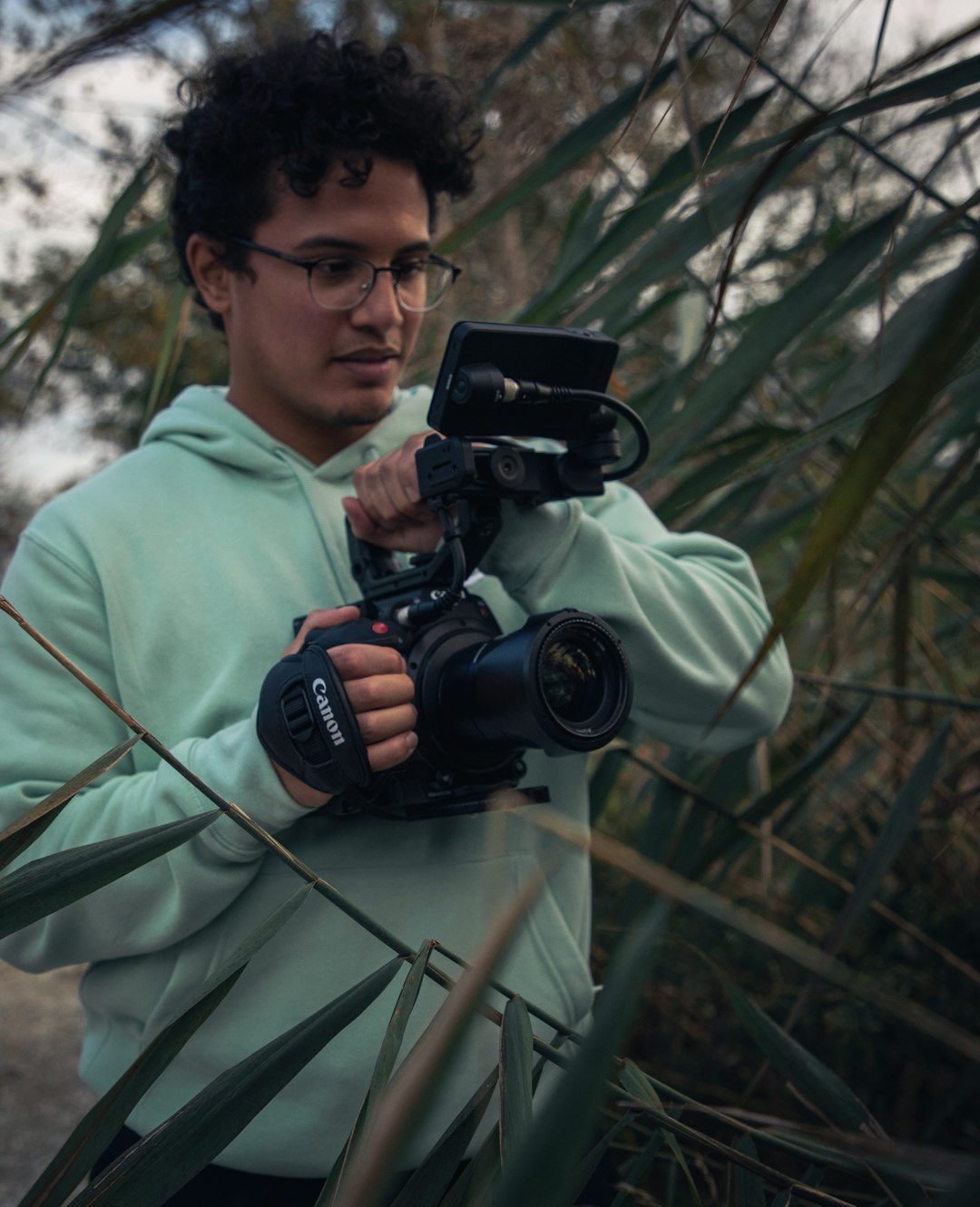 man in green hoodie holding black dslr camera