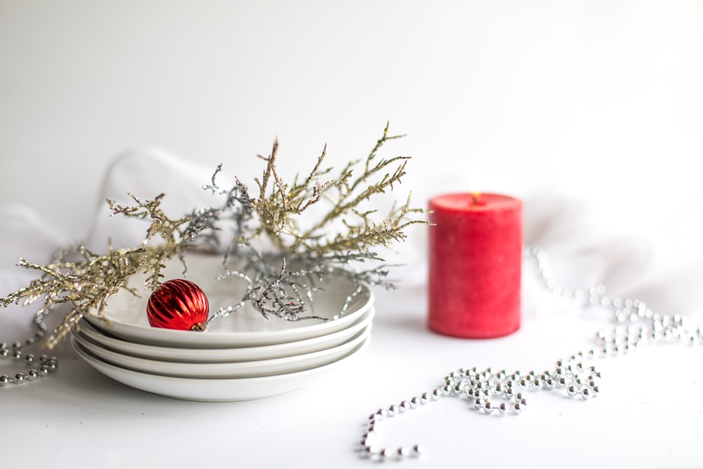 red pillar candle on white ceramic saucer